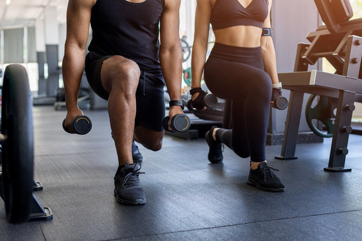 2 Menschen die einen Ausfallschritt im Fitnesstudio trainieren