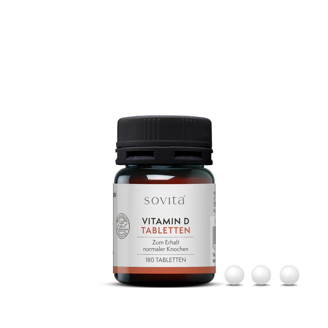 sovita Vitamin D Tabletten mit geöffneter Dose und drei weißen Tabletten im Vordergrund